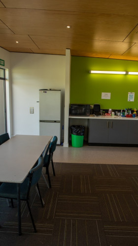 Oval VOC meeting room with table and 6 chairs. Small kitchenette in background